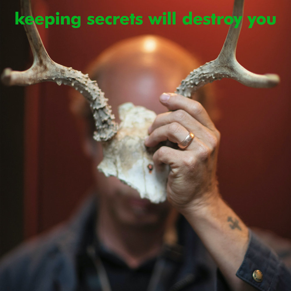 Album artwork. Bonnie Prince Billy holds antlers in front of his face. The song title 'Keeping Secrets Will Destroy You' is displayed at the top.